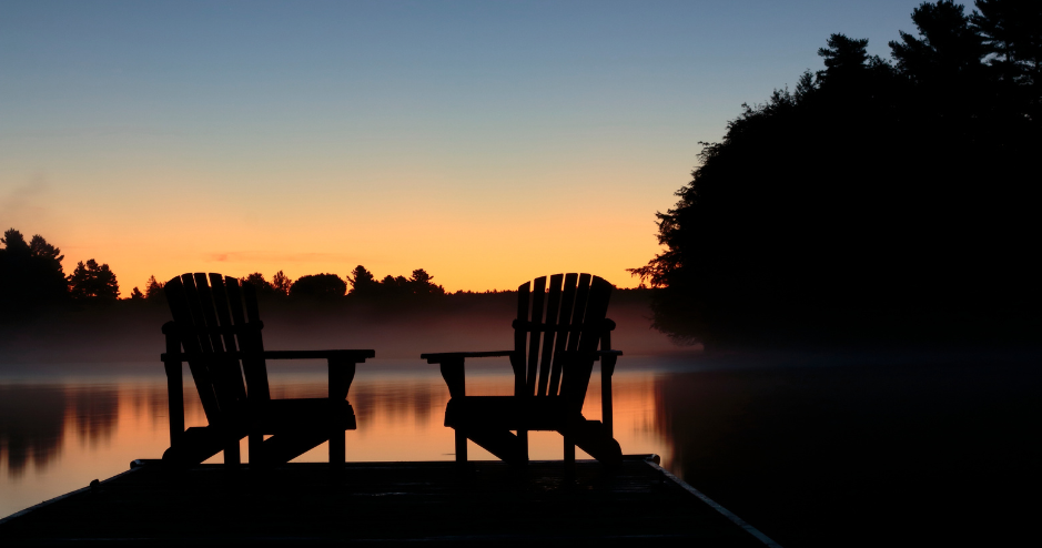 Two muskoka chair on the end of a dock at sunset