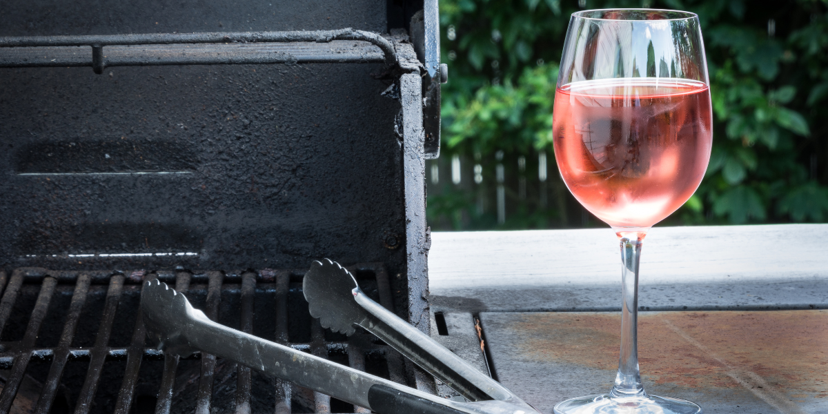glass of rosé next to a barbecue