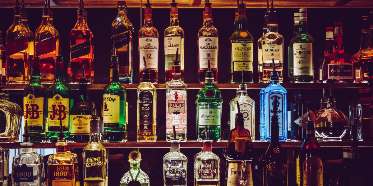rows of bottles behind a dark  bar