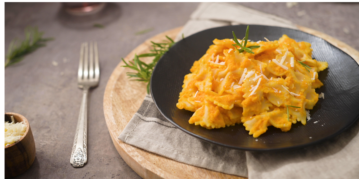 bowtie pasta in pumpkin bechamel sauce on a black plate