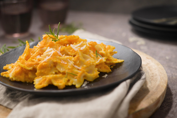 bowtie pasta in pumpkin bechamel sauce on a black plate