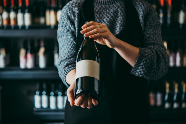 A dark image of a server presenting a wine bottle