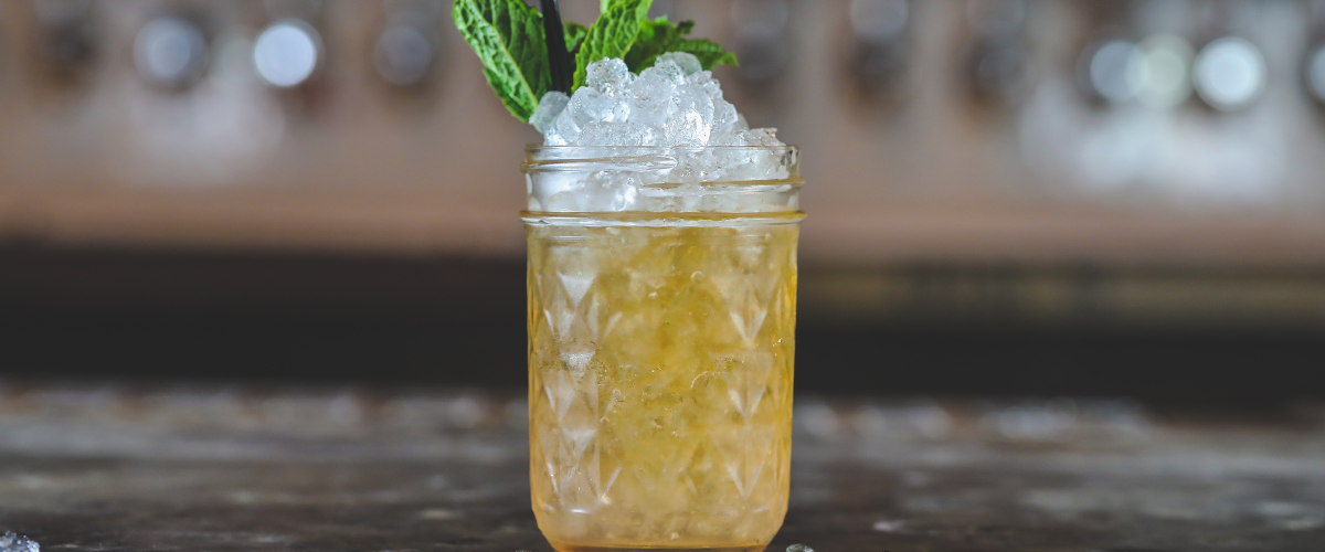 a whisky smash in a mason jar with crushed ice and mint sprigs