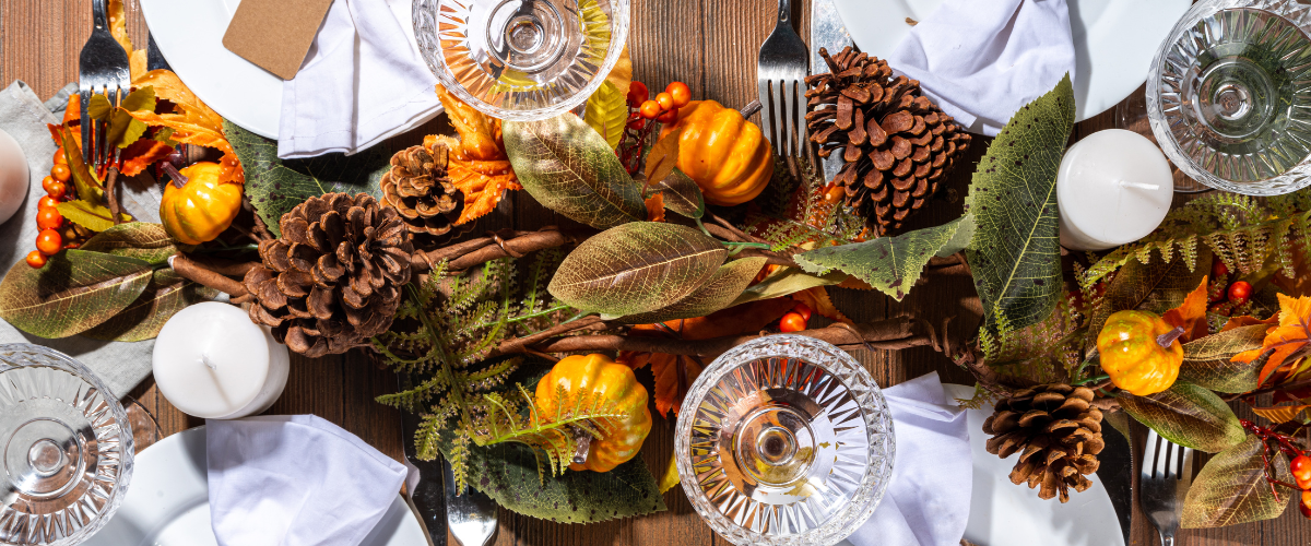 close up overhead view of a fall themed centre piece across a table set with plates and wine glasses