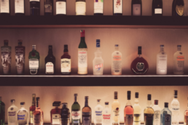 low lit bar shelf lined with unidentified bottles