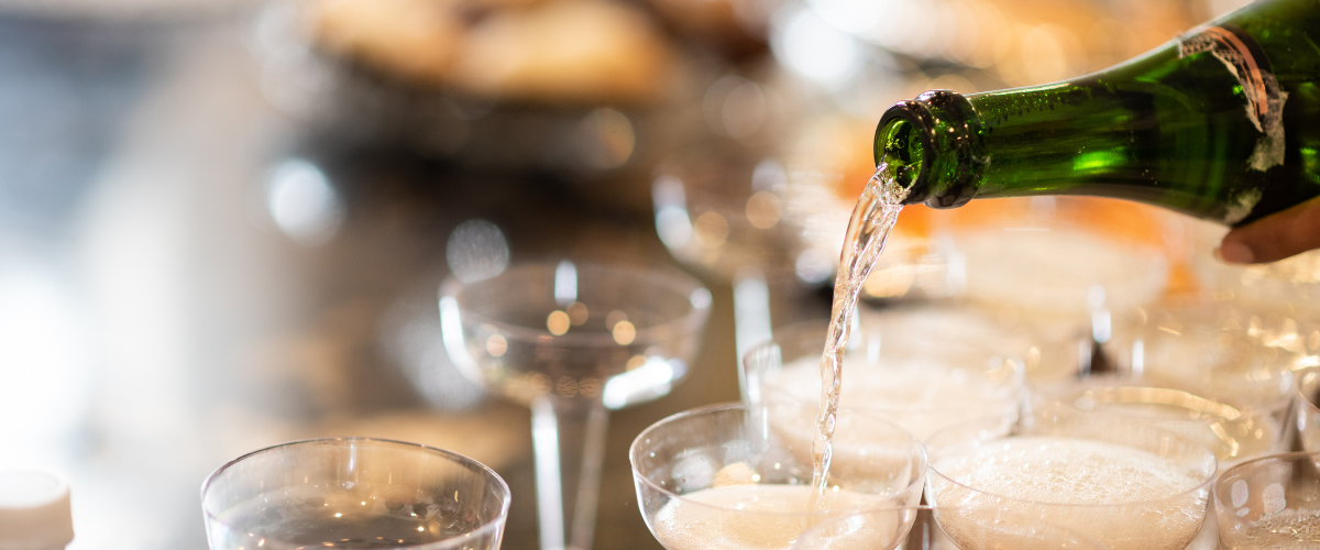 A bottle of bubbly being poured into festive coups