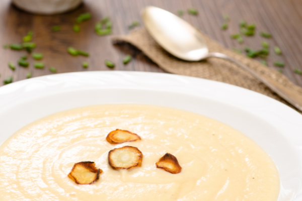 a bowl of smooth and creamy parsnip puree with toasted parsnip rounds