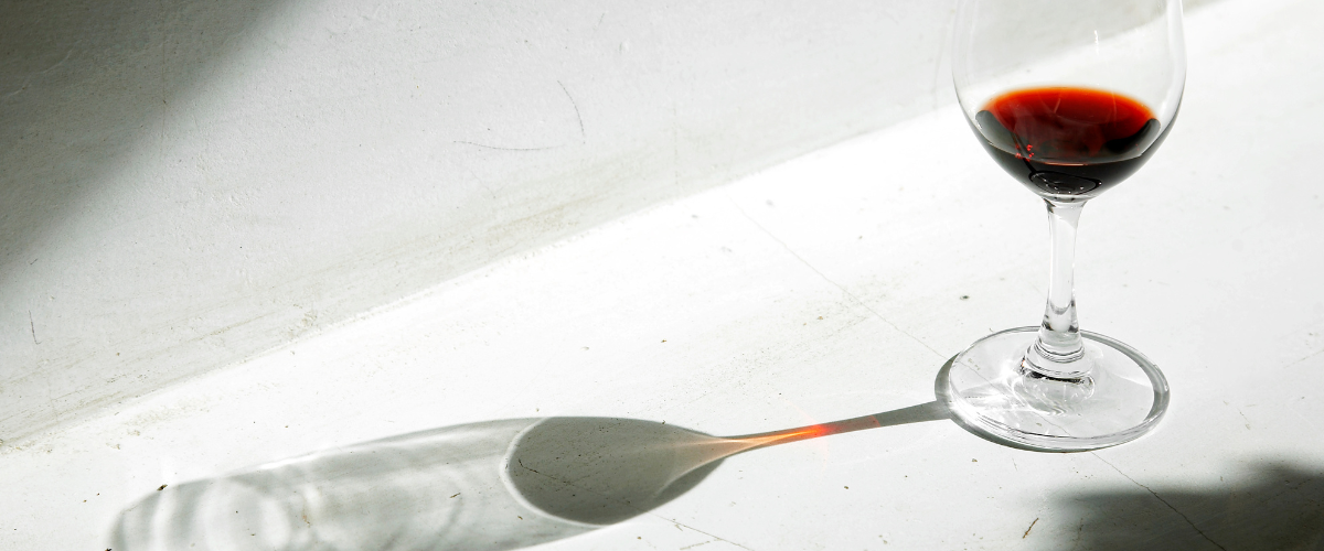 overhead view of a glass of red wine casting a long shadow
