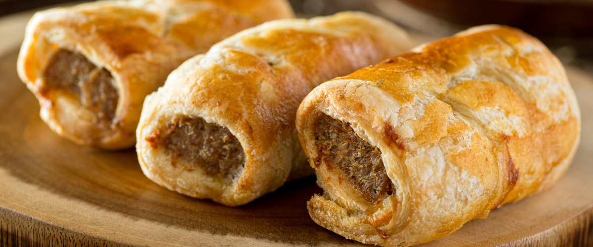 three sausage rolls stacked on a country counter