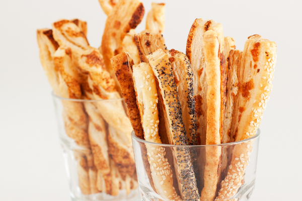 cheese straws standing upright in a cocktail glass