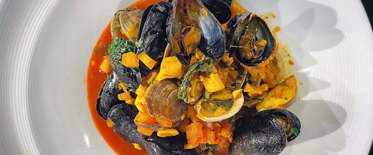 overhead view of a red seafood bisque in a white bowl