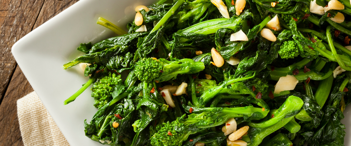 a white plate filled with bright green broccoli rabe and garlic