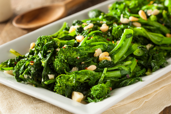 a white plate filled with bright green broccoli rabe and garlic