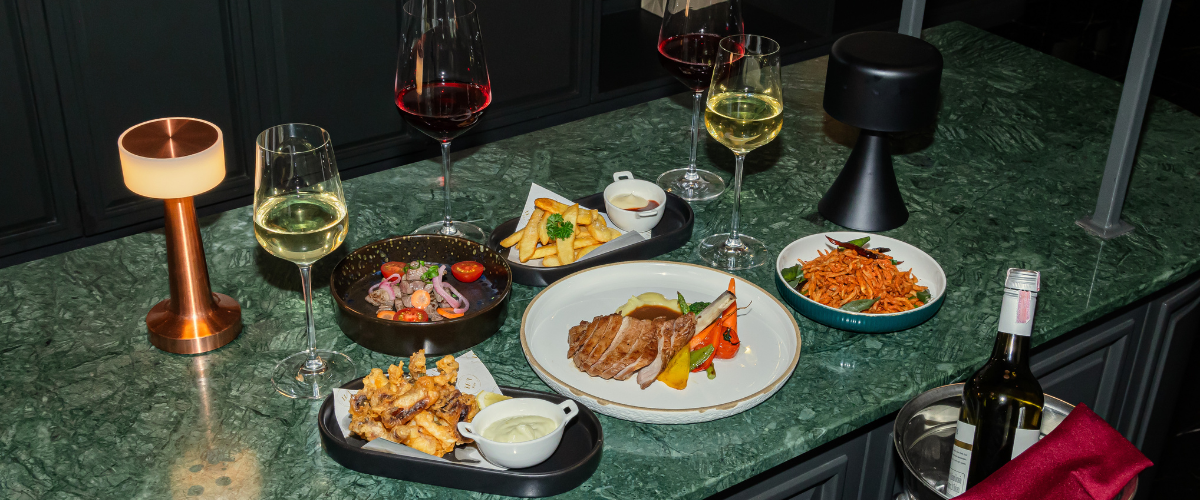 an overexposed, 70's glam styled buffet of various dishes on a green counter and a bottle of wine in an ice bucket