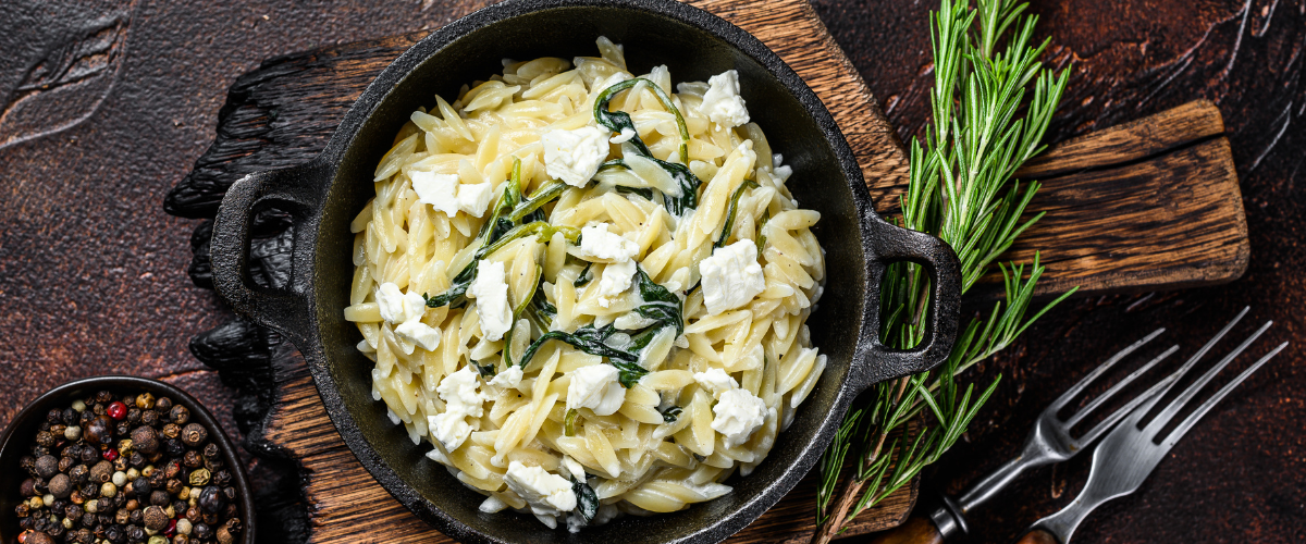 orzo and spinach in a mini cast iron pan on a wood board