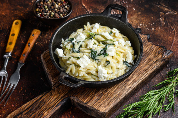 orzo and spinach in a mini cast iron pan on a wood board