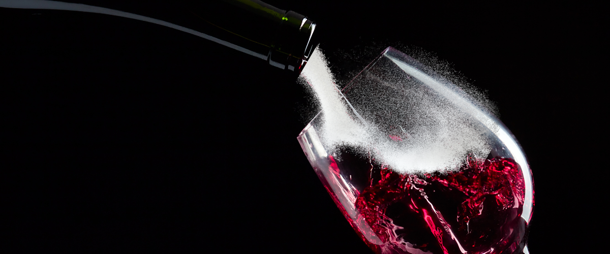 sugar streaming out of a bottle into a red wine glass