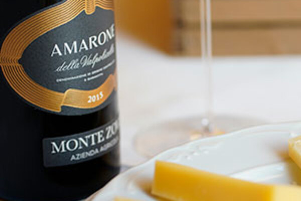 Bottle of amarone with a glass and a plate of cheese