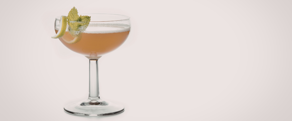 pinkish cocktail in a coup with foam