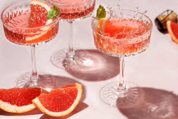 3 reddish-pink cocktails in a coup with grapefruit slices