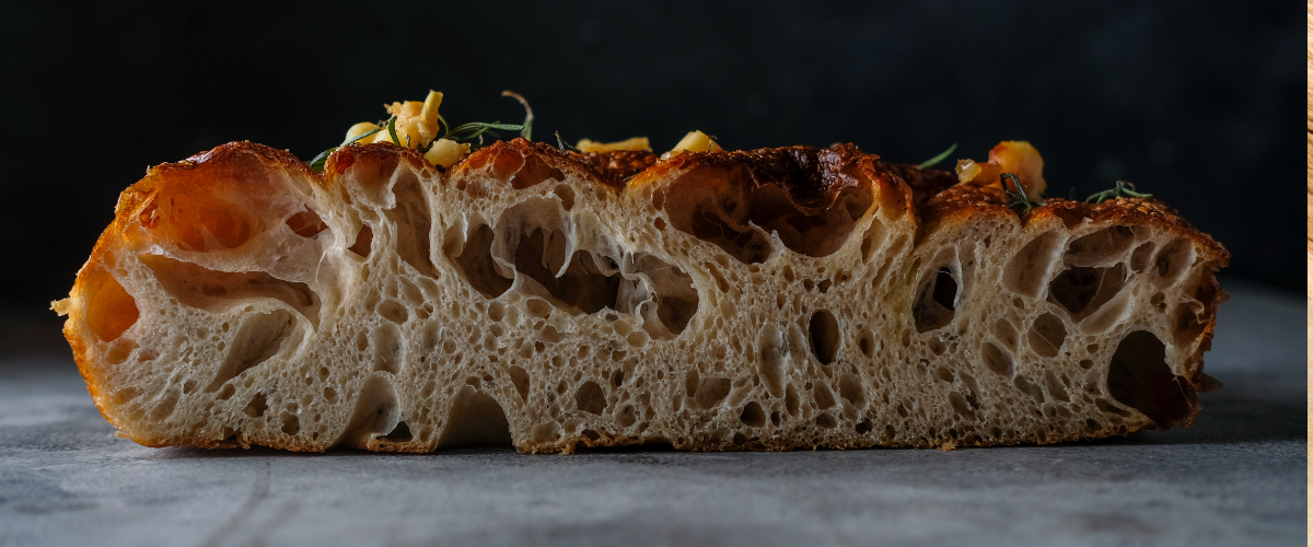 side view of bubbly focaccia against a black background