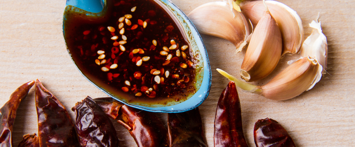 Mexican macha sauce in a blue bowl surrounded by chillis and garlic