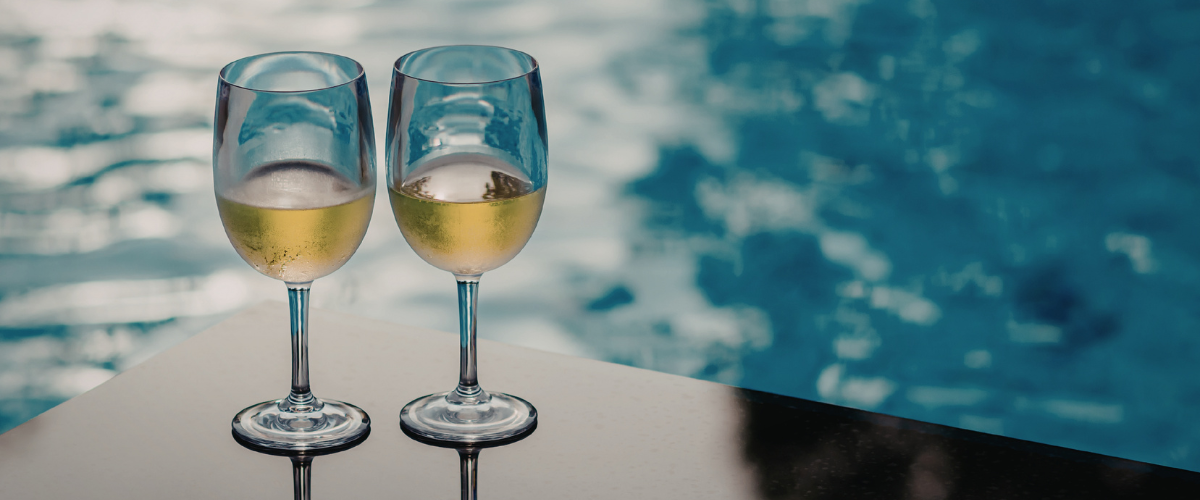 Two wine glasses by the pool