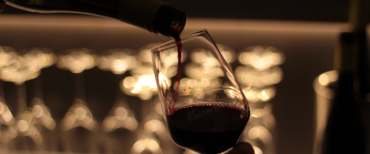 Moody backlit image of red wine pouring into a glass