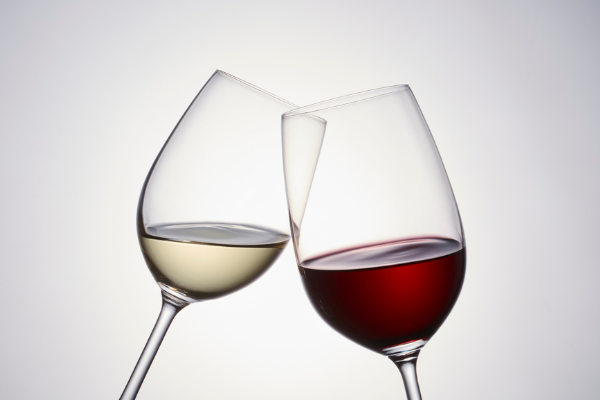 A glass of red and a glass of white wine clinking