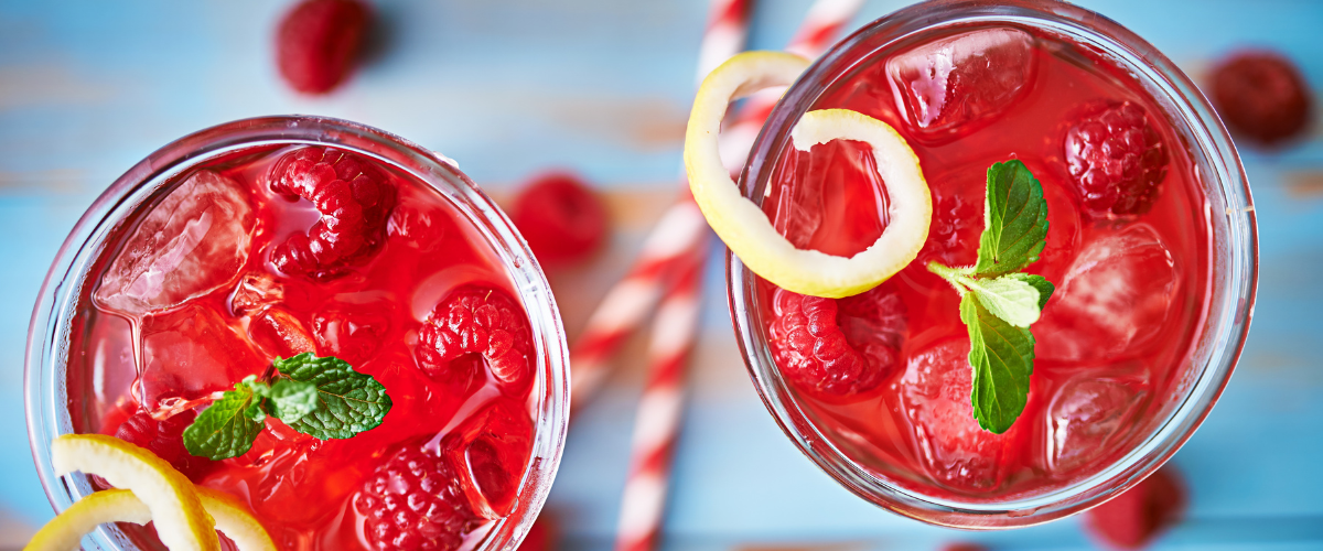 overhead view pink cocktails in rocks glasses with raspberry garnish