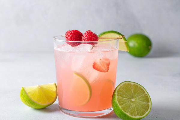 pink cocktail in a rocks glass with raspberry garnish