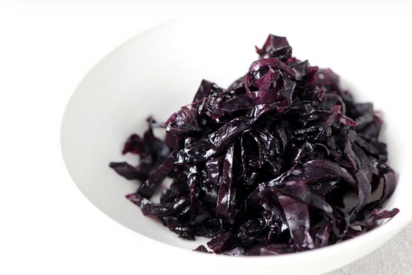 Purple braised cabbage in a white bowl against a white background