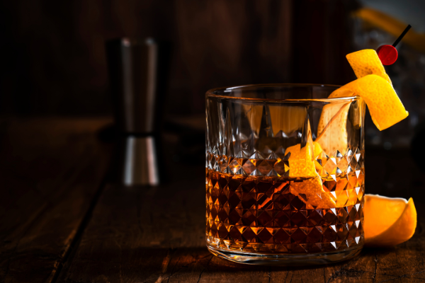 A tumbler of Sazerac against a dark background