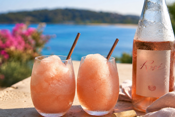 two glasses of frozé and a bottle against a lake