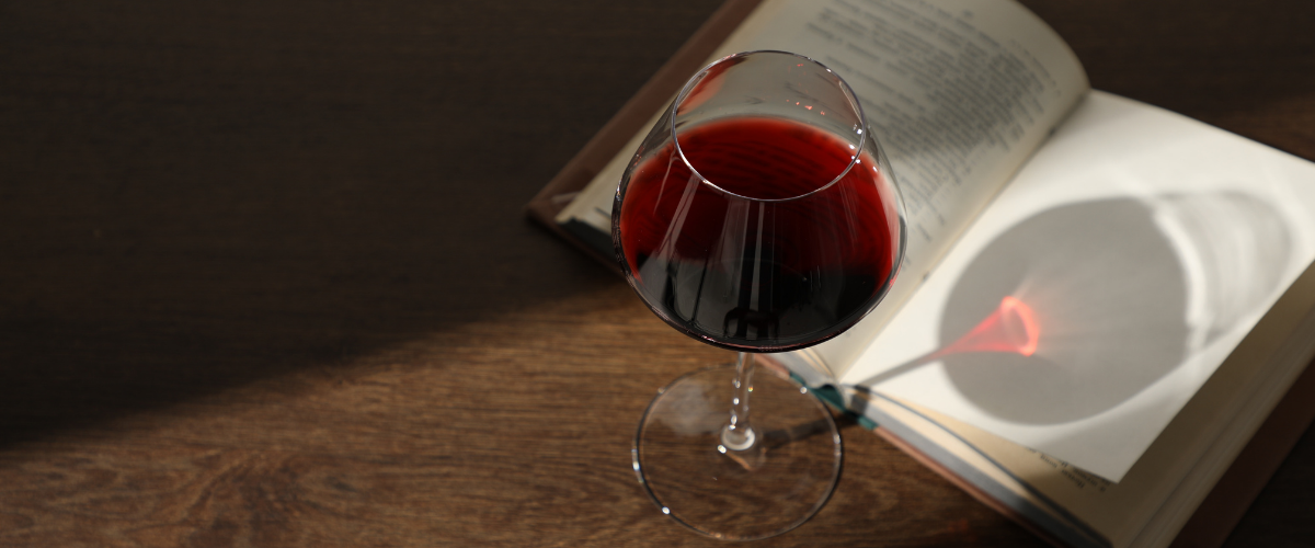 Glass of Wine throwing shadow on a  Book on Wooden Table.