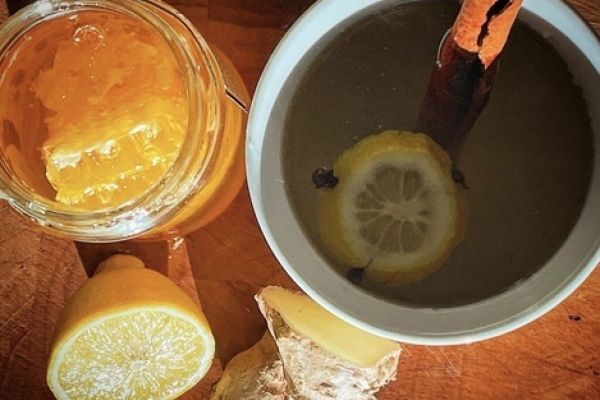 Hot toddy in a mug with lemon, honey and ginger