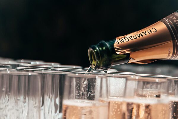 A bottle of champagne pouring into the tops of several flutes