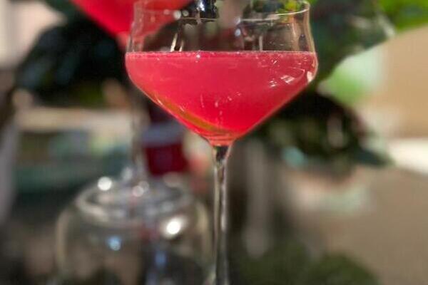 Side view of a bright fuchsia cocktail in a clear coup glass