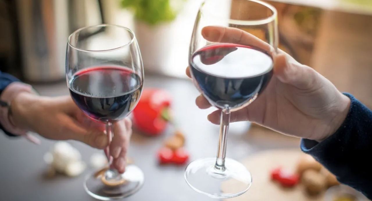 Man and woman clinking red wine glasses