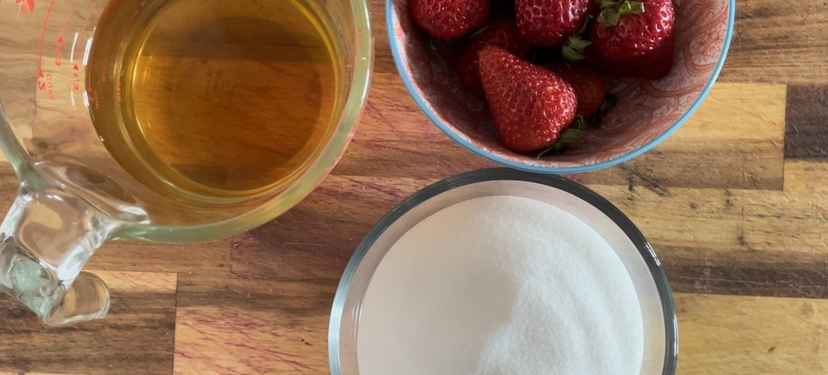 An overview picture of three bowls of strawberries, vinegar, and sugar