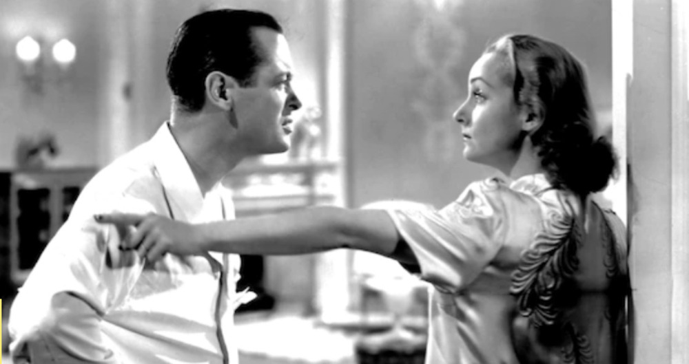A black and white image of an old movie where a man and woman are fighting