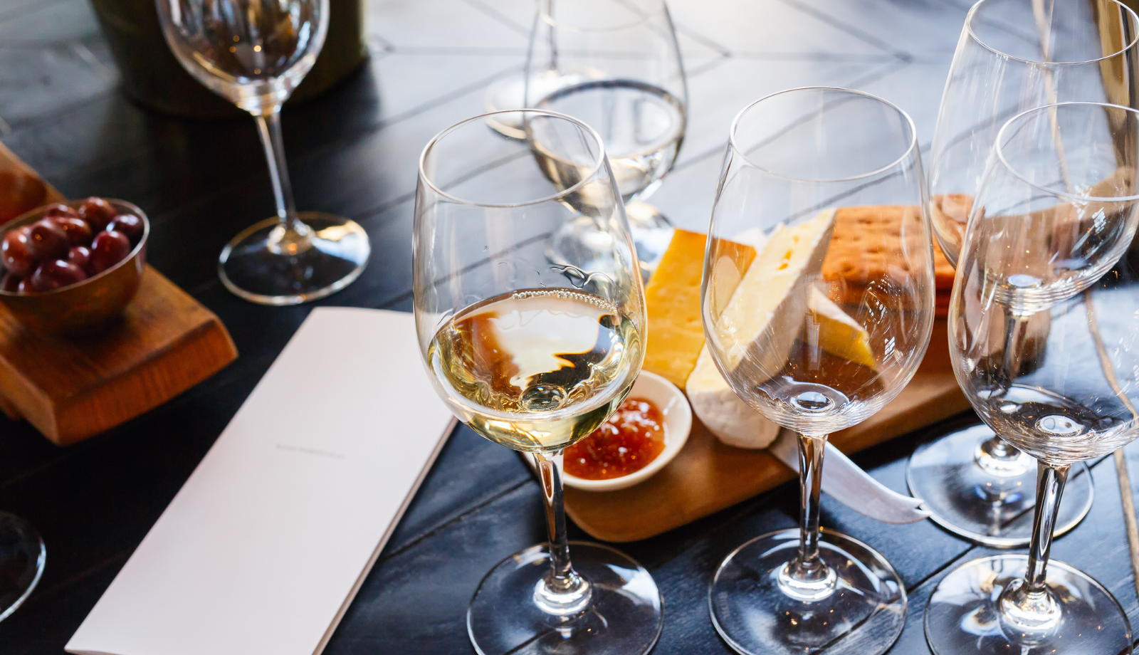 A scattering of wine glasses on a table with a pad of paper