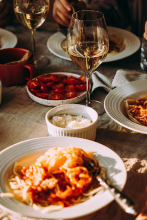 An Italian dinner table scattered with various plates of food and glasses of wine