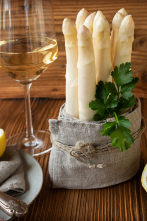 a bundle of upright white asparagus with a glass of wine
