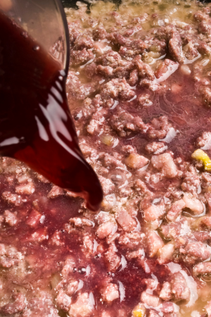 red wine pouring into meat sauce