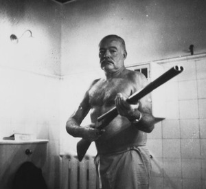 Ernest Hemingway, shirtless and holding a rifle