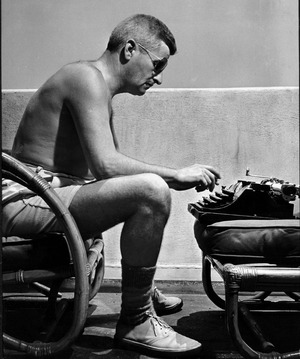 William Faulkner, shirtless and wearing aviators, typing on a typewriter