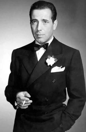 Humphrey Bogart wearing a tuxedo and smoking a cigarette