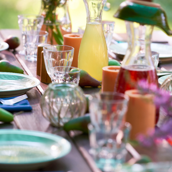 An outdoor table in the sunlight set for a party