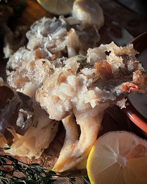 close up of a fried mushroom, a wedge of lemon and fresh thyme sprigs beside it